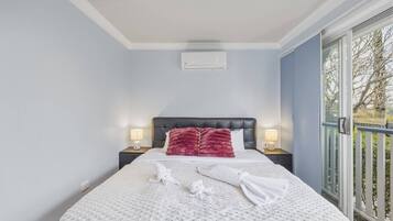 Una camera d'albergo con un letto, un comodino, una finestra vista e un climatizzatore a soffitto.