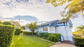 A two-story house with a blue and white exterior, a well-maintained lawn, and a clear sky.