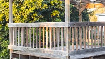 A wooden deck with a pergola structure, surrounded by greenery.