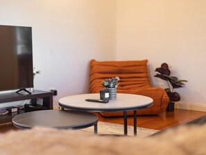 A modern living room with a flat-screen TV, a round coffee table, a sofa, and a small plant. - Character Home| Mt Coot-tha Views | Prime location (Sherwood)