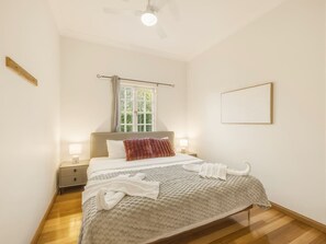 A bedroom with a bed, bedside tables, a window, and a ceiling fan. - Character Home| Mt Coot-tha Views | Prime location (Sherwood)