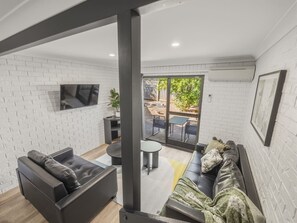 A modern living room with a sofa, a coffee table, and a TV mounted on the wall. - GreatValue Stay| Pool | Parking | Prime Location (Eight Mile Plains)