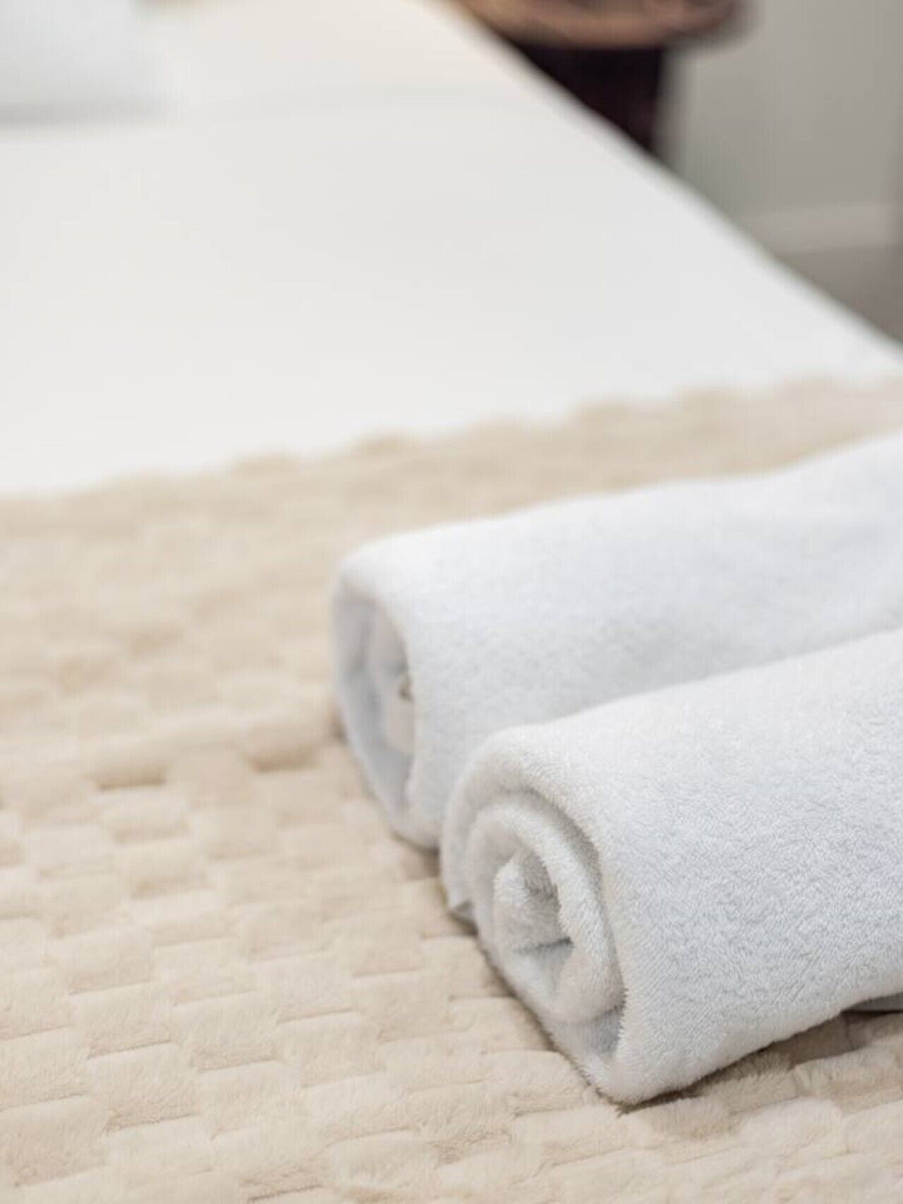 A neatly folded white towel on a textured beige bedspread.