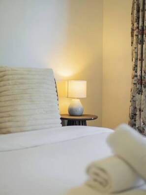 A hotel room with a bed, a bedside lamp, and a floral curtain. - Affordable Stay | Near Sunnybank |Prime Location (Robertson)