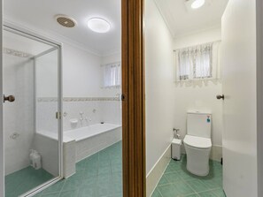 Een badkamer met douche, bad, toilet en wastafel.