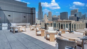 A rooftop terrace with outdoor seating and a city skyline view. - Wabash 4BR - Pool, Free In & Out Parking 1 (Chicago)