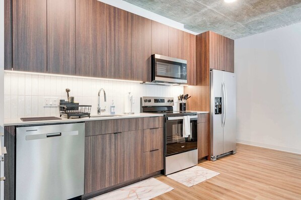 A modern kitchen with wooden cabinets, stainless steel appliances, and a white tiled backsplash.