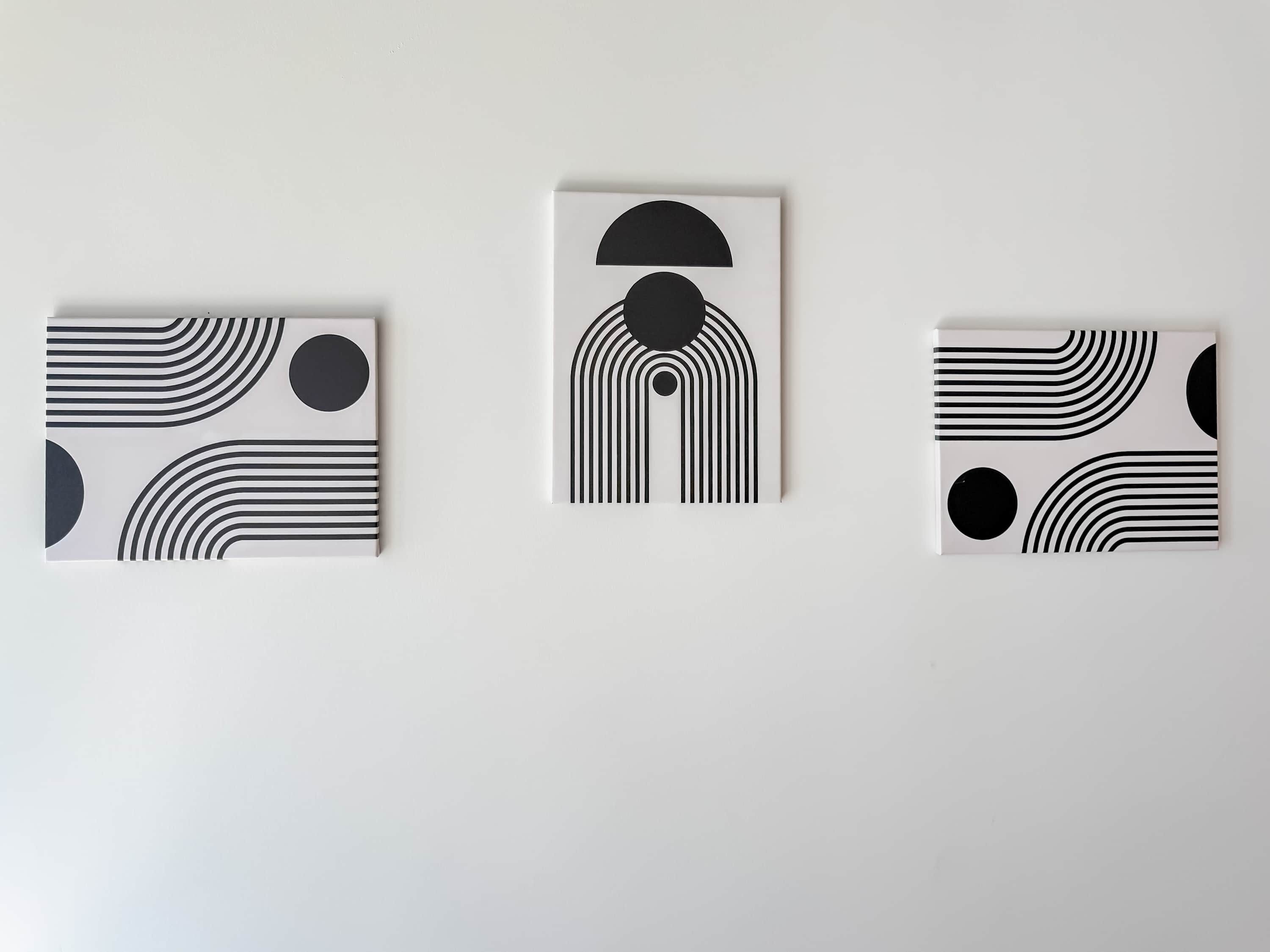 Three framed abstract artworks on a plain wall.