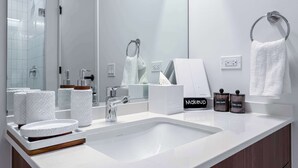 A modern bathroom with a large mirror, a white sink, and a towel rack. - Wabash 4BR - Pool, Free In & Out Parking 2 (Chicago)