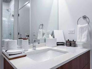 Un bagno moderno con uno specchio grande, un lavandino bianco e un portascopevoli.