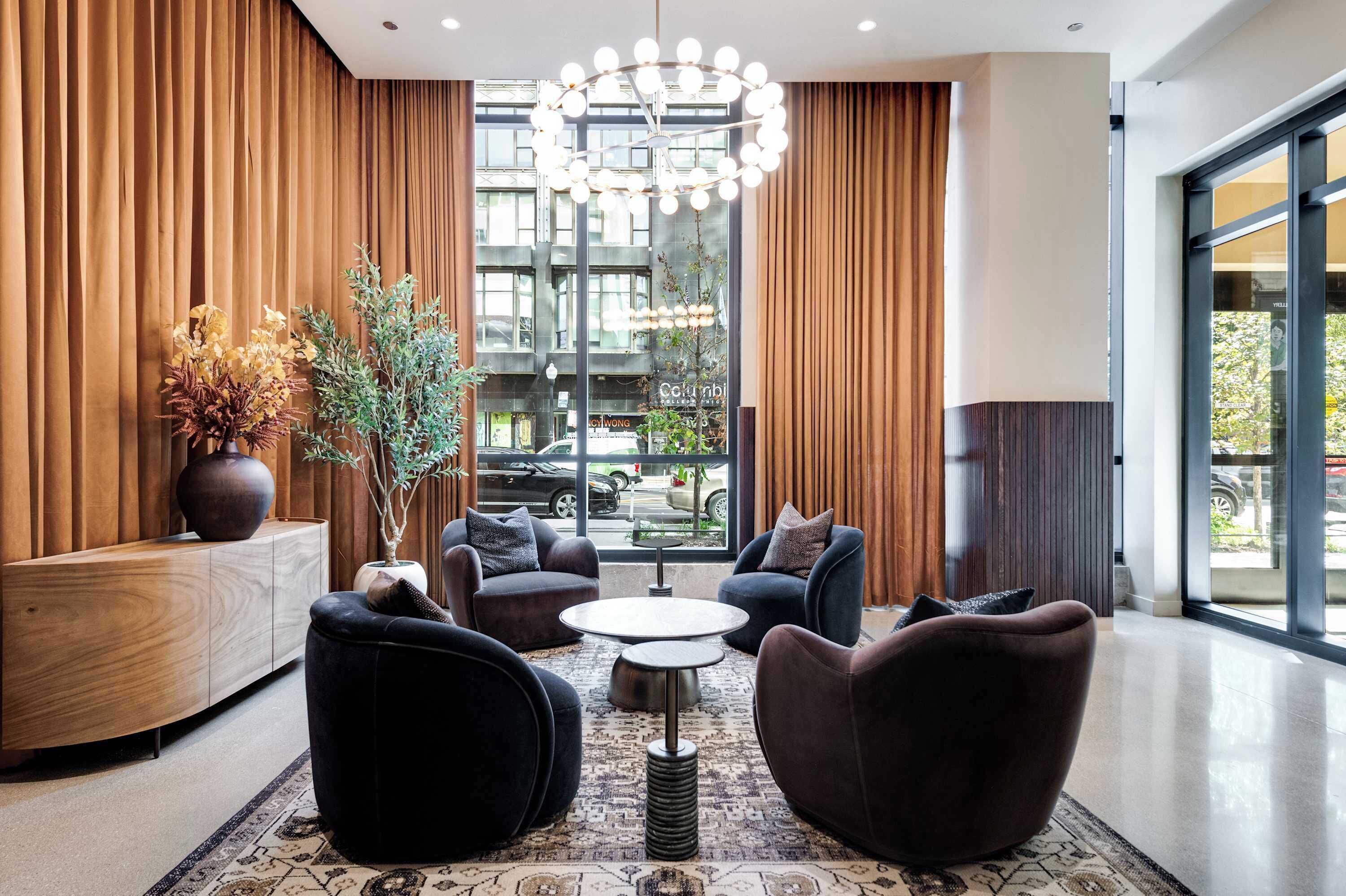Um lobby moderno com balcão de recepção, área de estar e grandes janelas com vista para a rua.