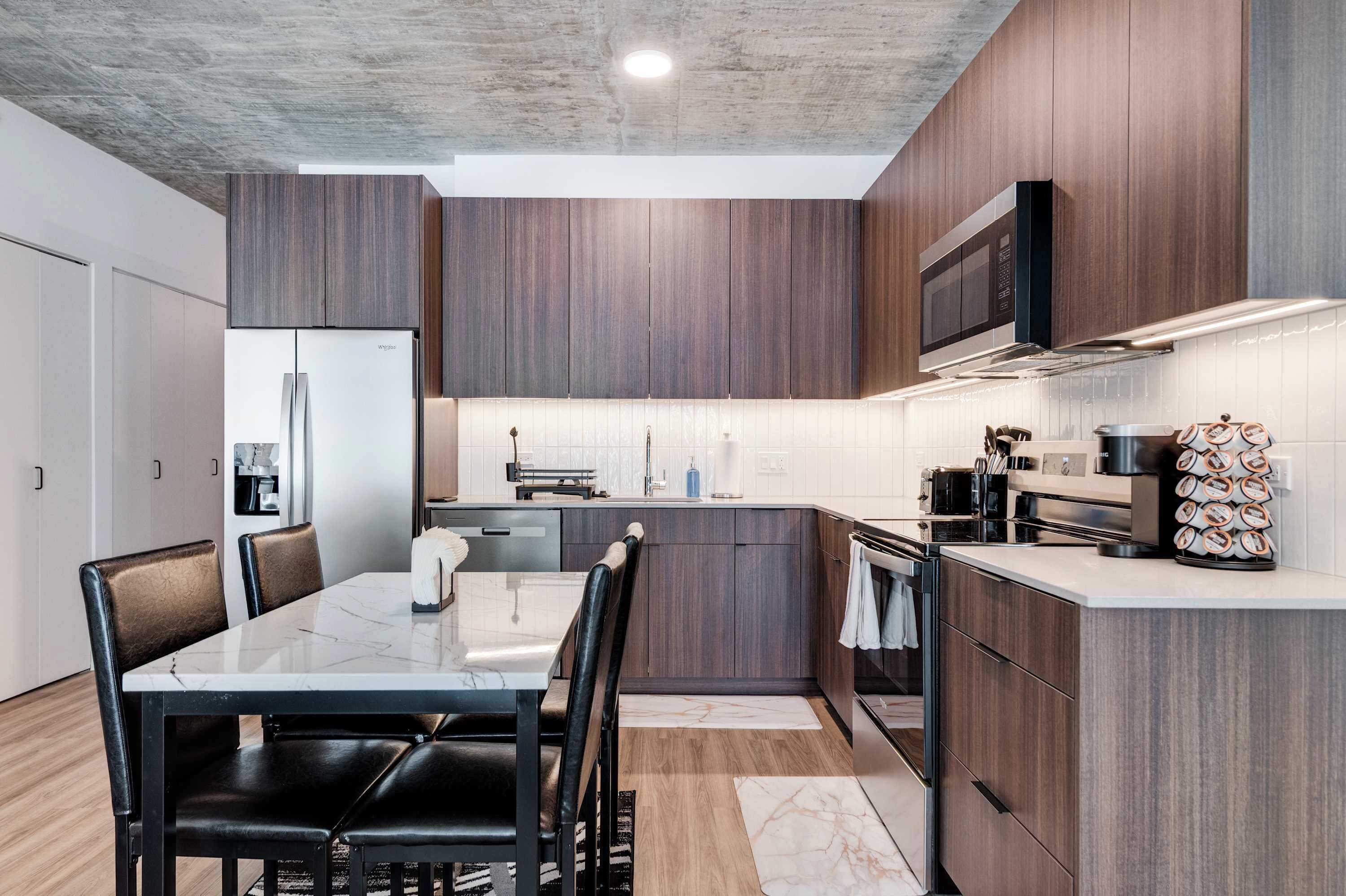 A modern kitchen with dark wood cabinets, a built-in microwave, and a stainless steel range hood.