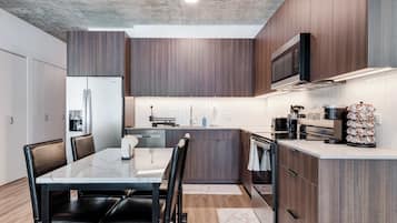 A modern kitchen with dark wood cabinets, a built-in microwave, and a stainless steel range hood.