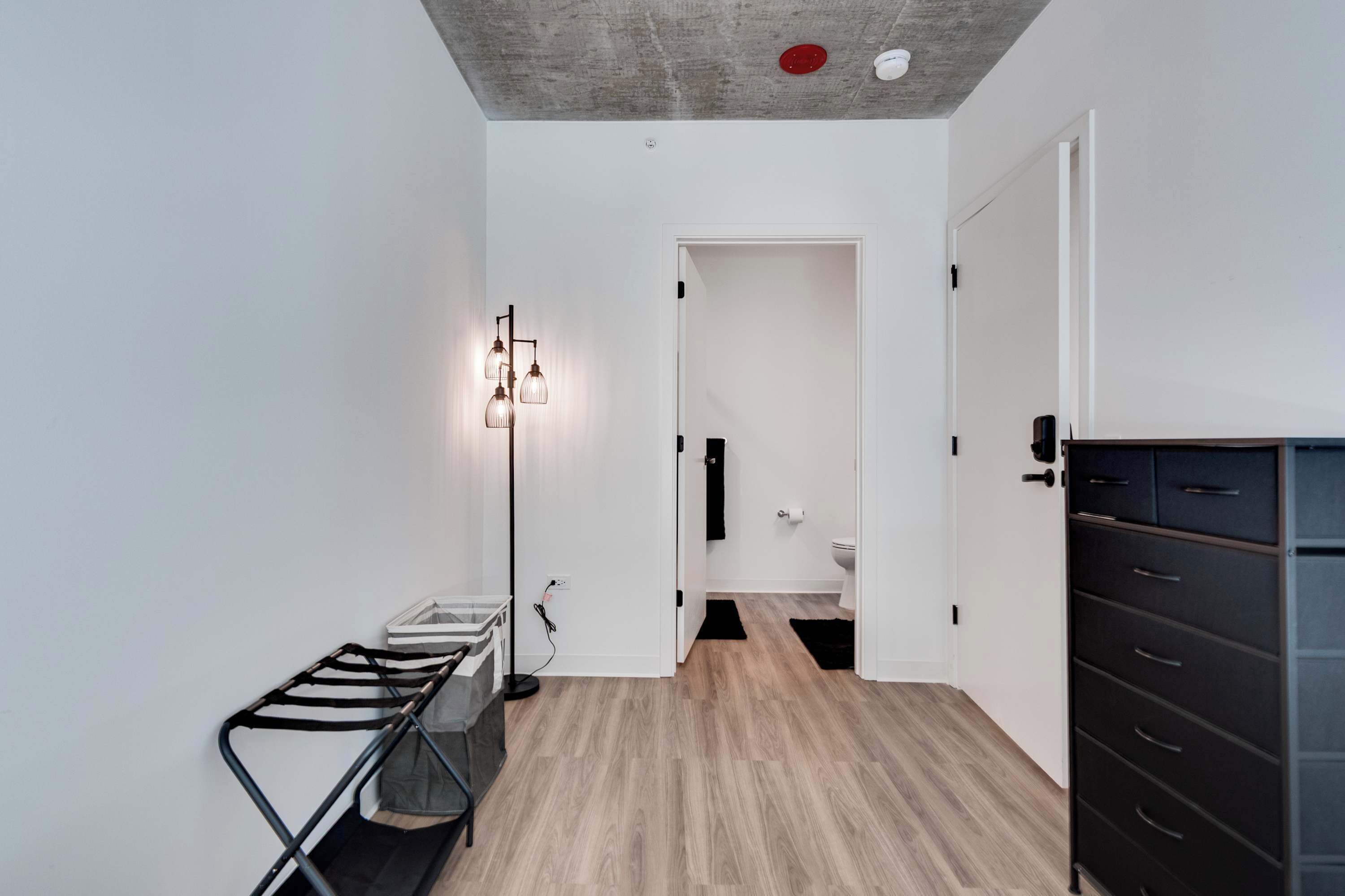 Corredor com luminária moderna, um banco e um armário.