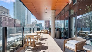 Terraza en la azotea con mobiliario exterior, un contenedor de basura y vistas del horizonte urbano.