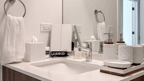 Un baño moderno con un espejo grande, un lavabo blanco y un perchero para toallas.