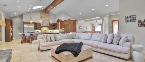 A spacious living area with a sectional sofa, a coffee table, and a kitchen in the background.