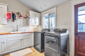 Eine Küche mit weißen Schränken, einer Holzausziehtafel, einer Waschmaschine und einem Trockner.