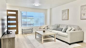 Una sala de estar moderna con sofá, mesa de centro y mueble para televisor.