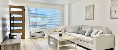 Ein modernes Wohnzimmer mit Sofa, Couchtisch und TV-Möbel.