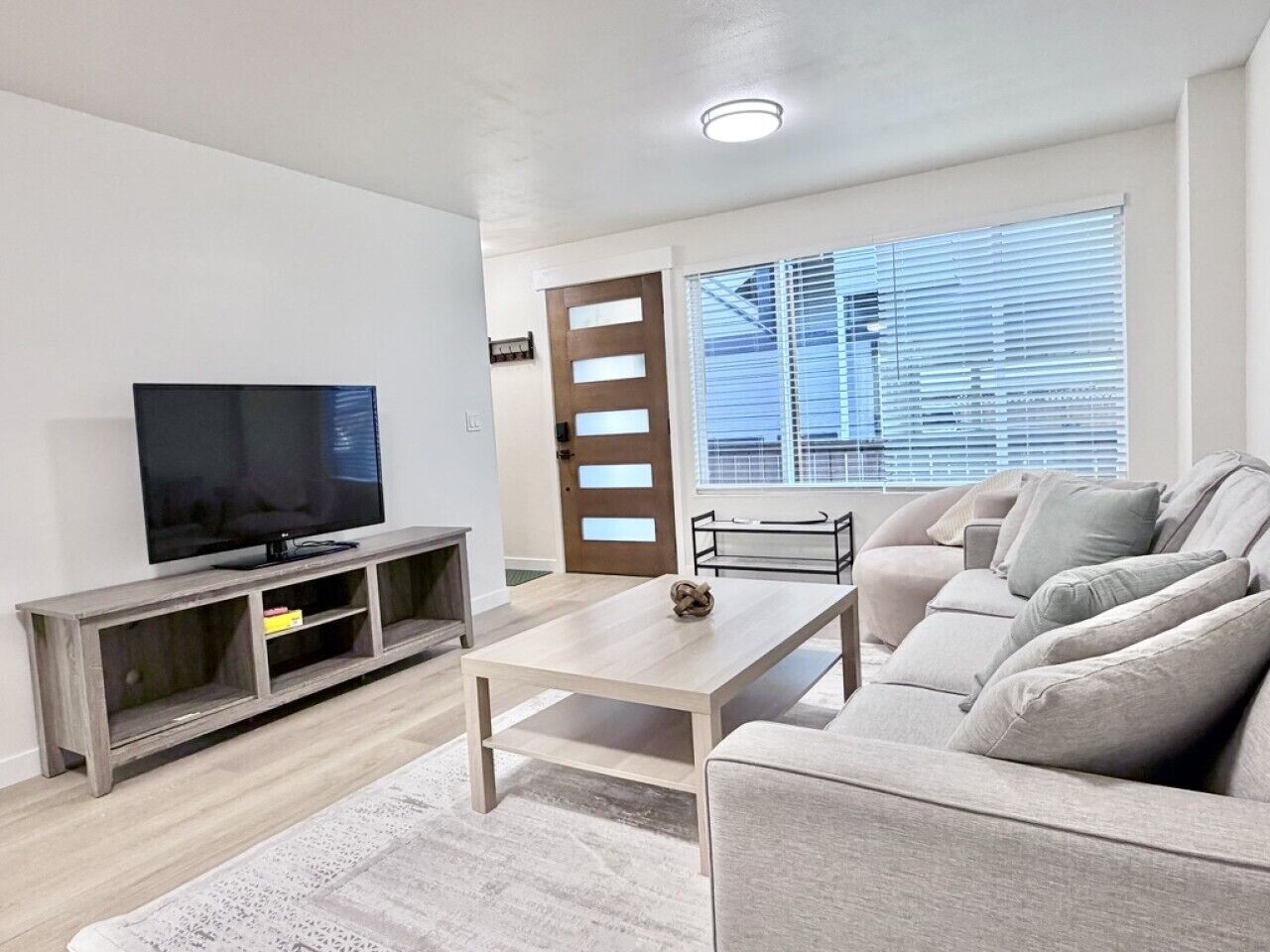 Un salon comprenant un téléviseur, un canapé, une table basse et une porte avec une fenêtre.
