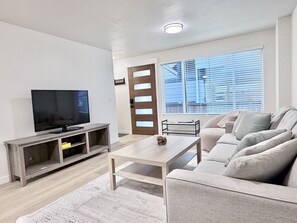 Un salon comprenant un téléviseur, un canapé, une table basse et une porte avec une fenêtre.