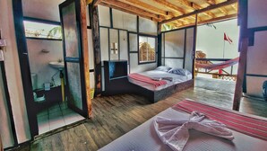 Quarto com cama, uma mesinha, janela e vista para o exterior.