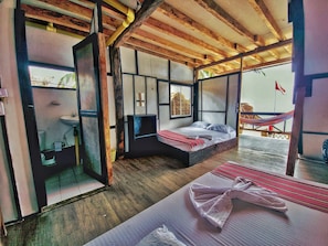 A room with a bed, a small table, a window, and a view of the outside. - El Rincon de Juan (san onofre)