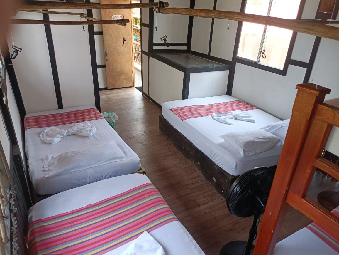 Una habitación con literas, un ventilador y un escritorio de madera.