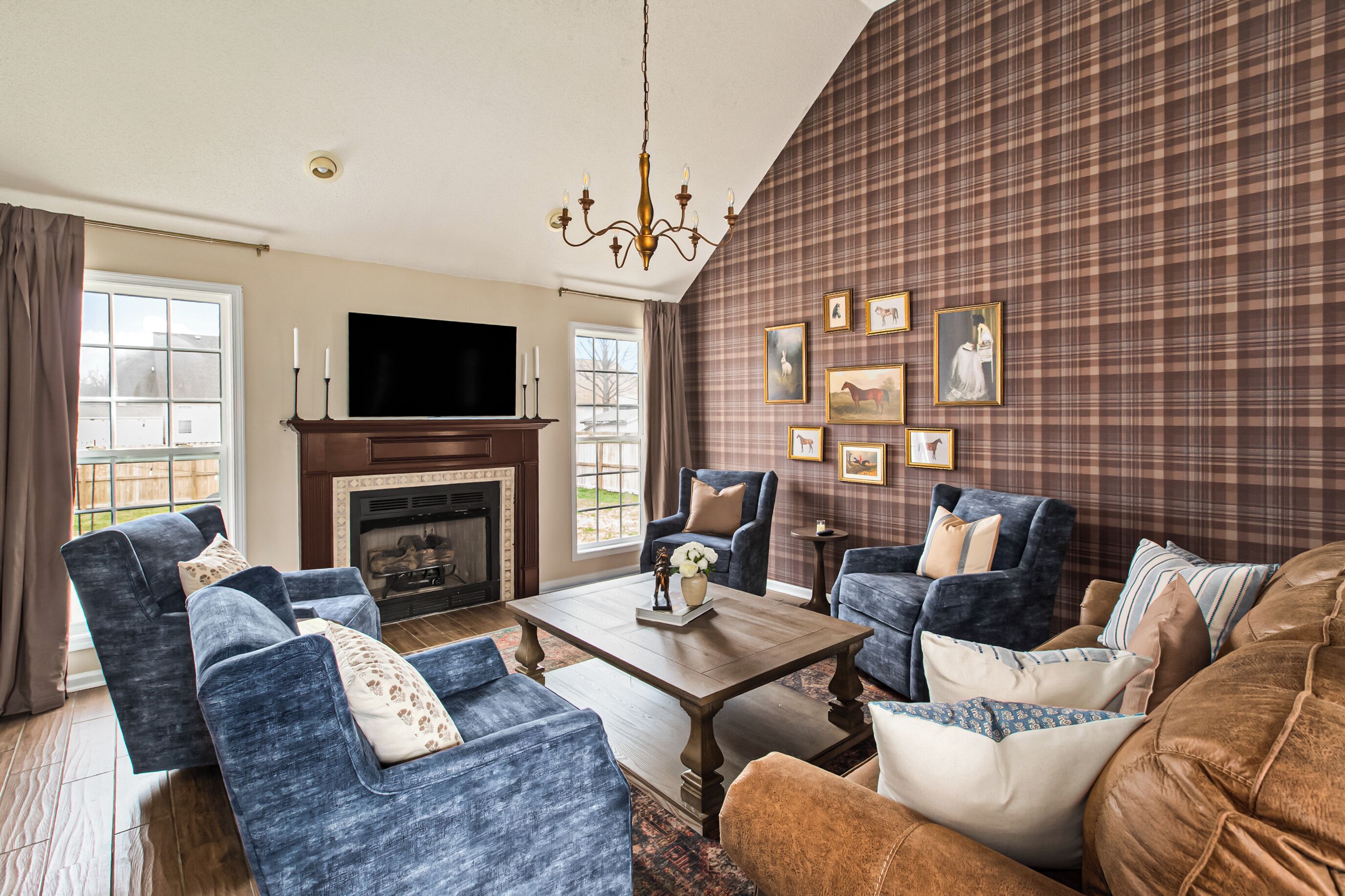 A living room with a fireplace, blue sofas, a coffee table, and plaid wallpaper.
