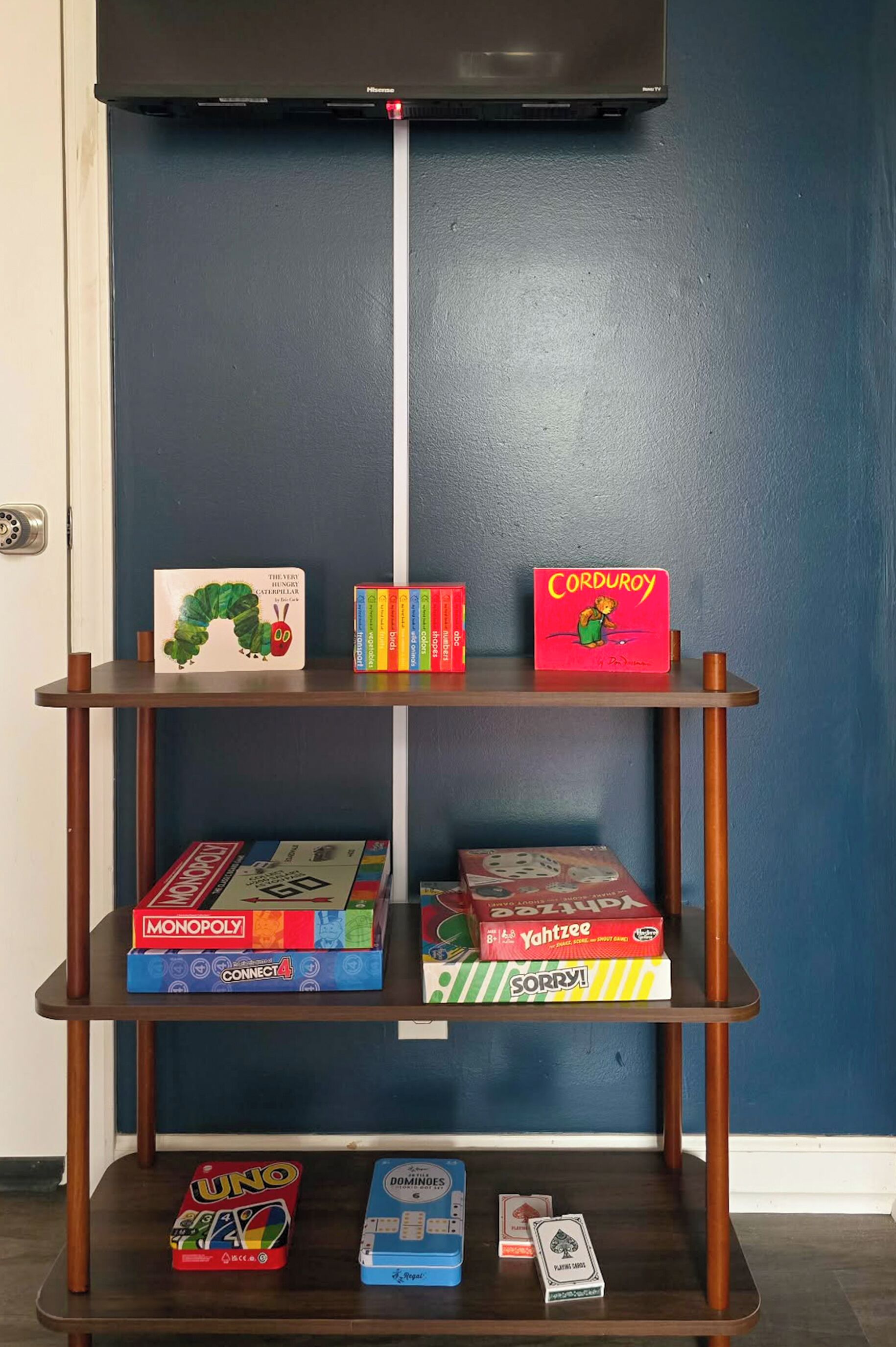 Una estantería con varios juegos de mesa y un televisor encima.