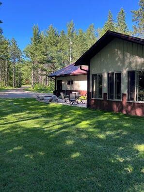 A lodge with a covered patio, a dining area, and a large windowed room. - Private and quiet retreat ,three blocks to the paved bike trail, (Deerwood)