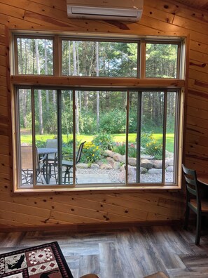 A room with a large window overlooking a garden with a patio table and chairs. - Private and quiet retreat ,three blocks to the paved bike trail, (Deerwood)