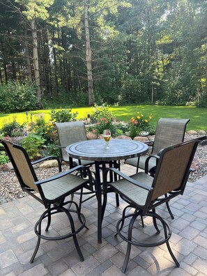 A round outdoor table with four chairs, surrounded by a garden with various plants and flowers. - Private and quiet retreat ,three blocks to the paved bike trail, (Deerwood)