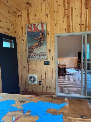 A wooden interior with a ski-themed poster, a fan, and a map on the table. - Private and quiet retreat ,three blocks to the paved bike trail, (Deerwood)