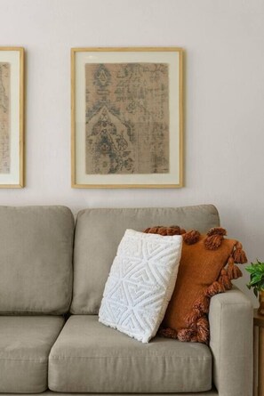 A sofa with a white throw pillow and a brown blanket with tassels. - Boho Palms by Coastline Vacation Rentals (San Diego)