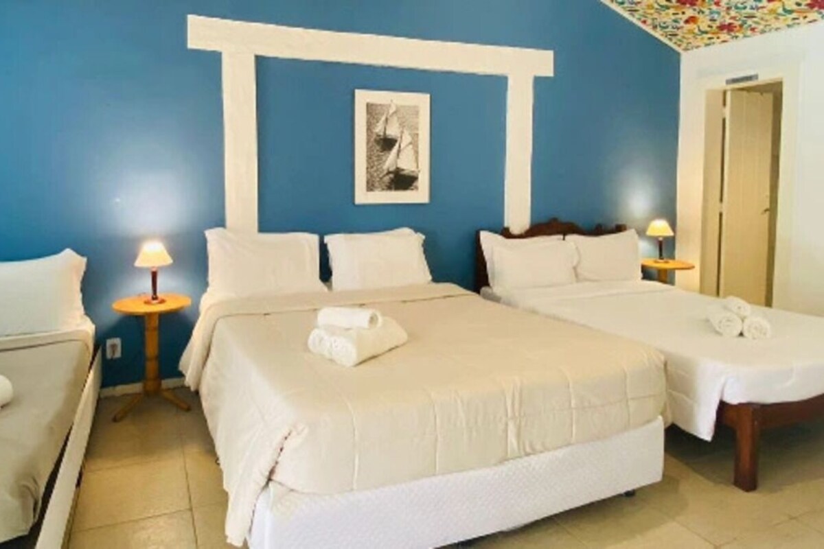 A hotel room with two beds, a sofa, a lamp, and a framed picture on the wall.