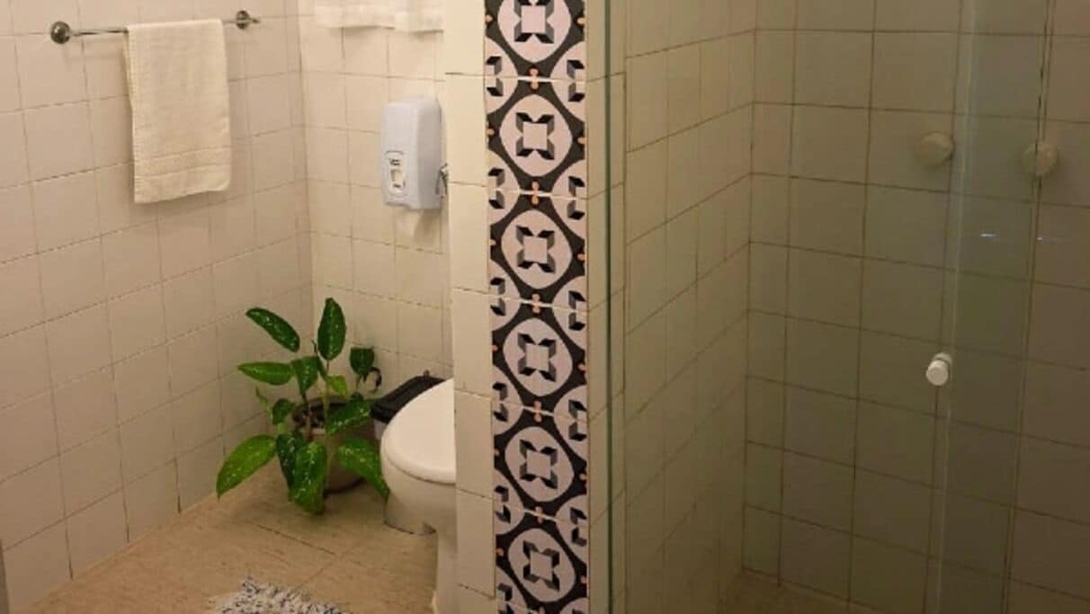 A bathroom with a toilet, a sink, a towel rack, and a shower area.