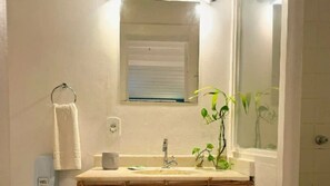 A bathroom with a sink, mirror, towel rack, and a small window. - POUSADA DOS PÁSSAROS (Rio de Janeiro)