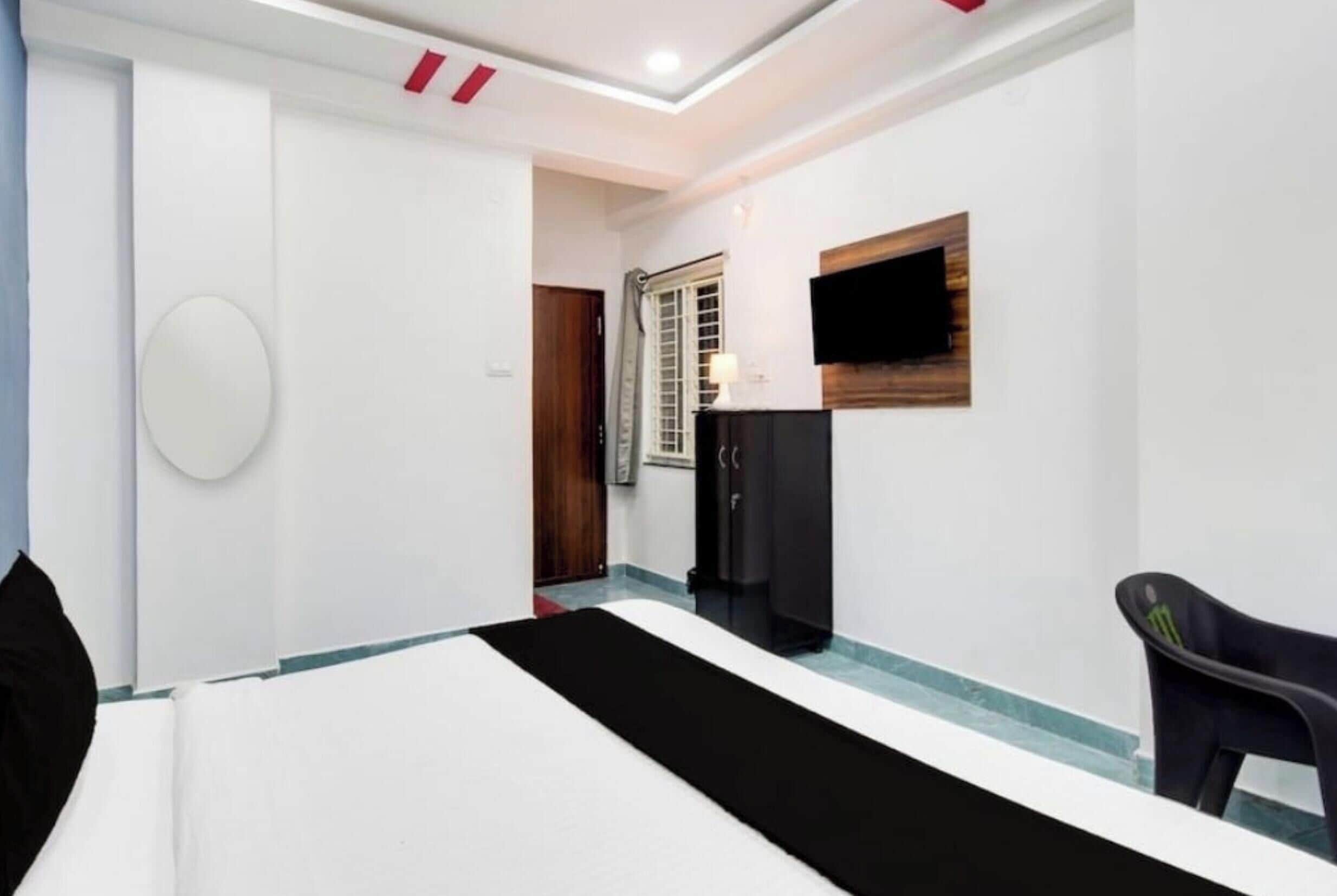 Habitación de hotel con cama, televisor montado en la pared, armario y una silla.