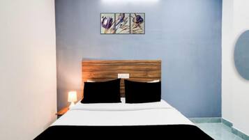 Una habitación de hotel con una cama, una mesita de noche, una lámpara y una obra de arte colgada en la pared.