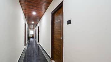 A long, narrow hallway with wooden ceiling panels and a black carpeted floor.