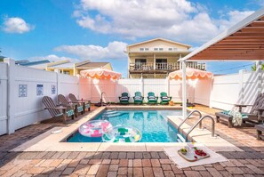 A backyard with a swimming pool, lounge chairs, and a covered patio area. - MilSViewsI PoolI BarrelSaunaIGulf ViewsI25Steps2BeachIGame RoomIPCB Beachlife (Panama City Beach)