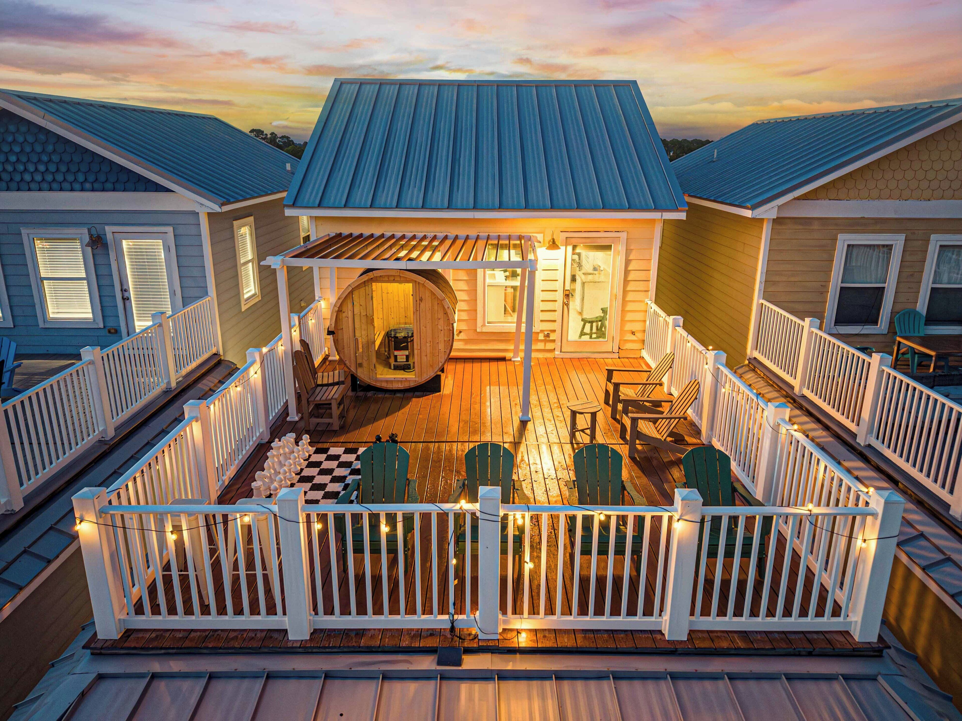 A wooden deck with a checkered floor, surrounded by white railings, and a sauna in the center.