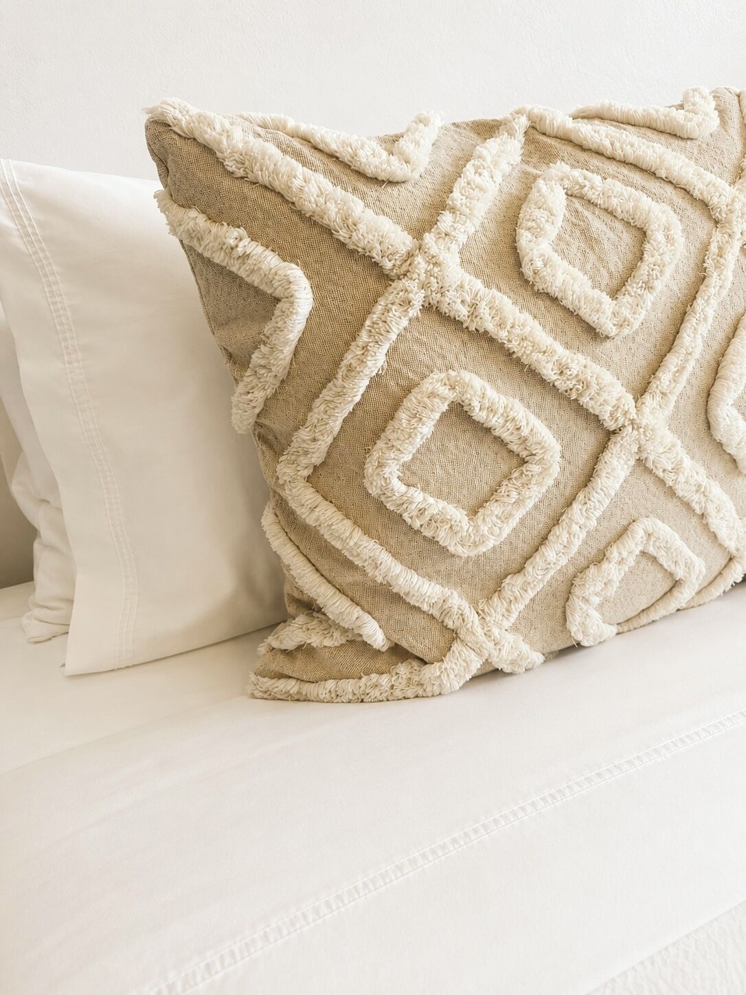 Un oreiller à motifs en relief sur un lit blanc.
