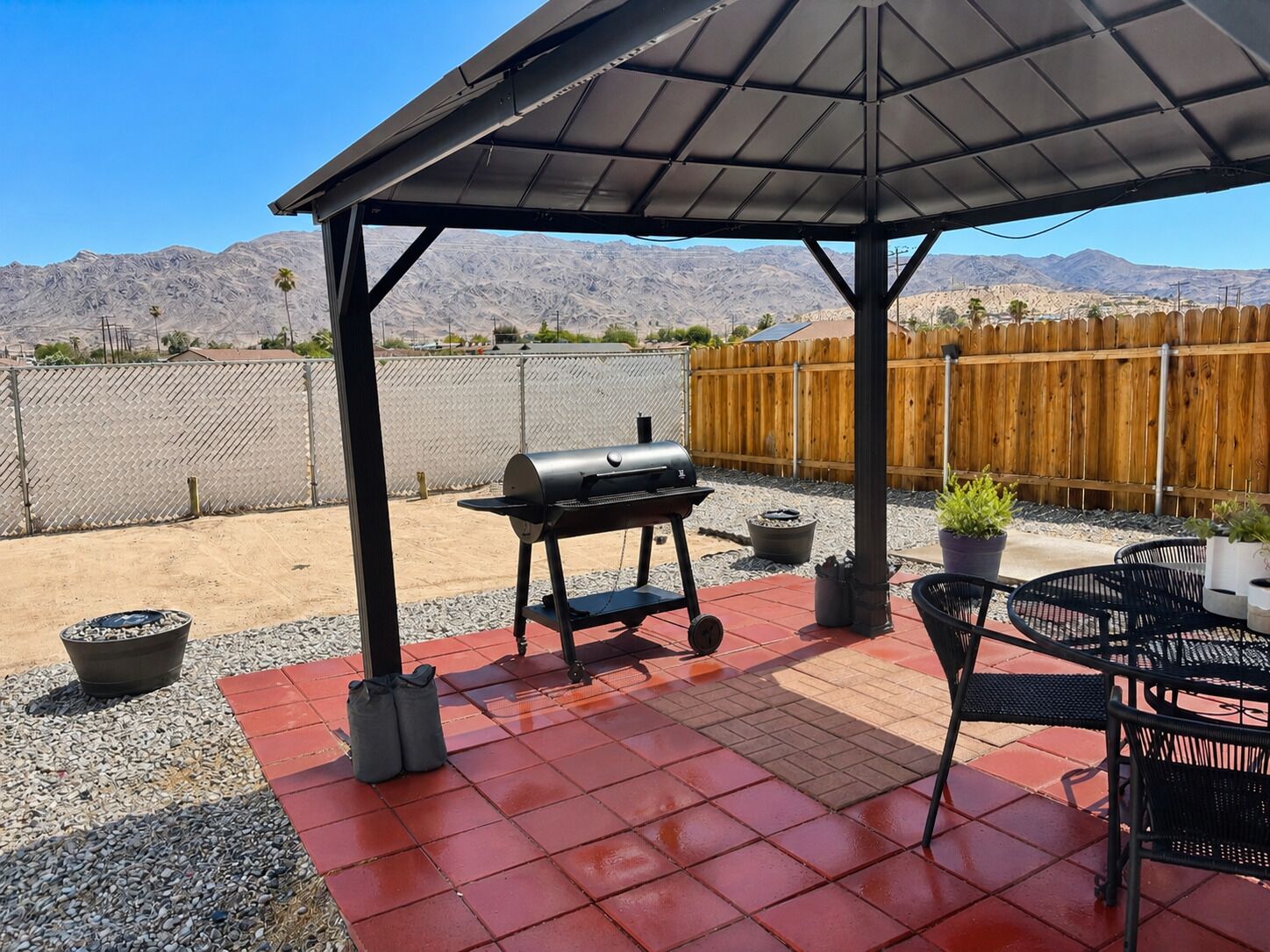 An outdoor patio with a barbecue grill, seating area, and a view of mountains.