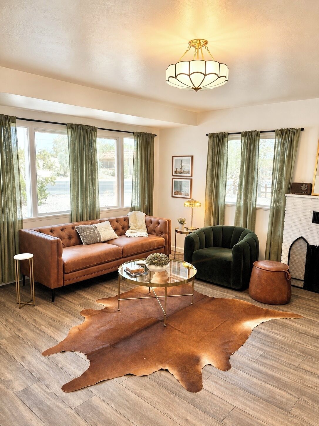 A living room with a leather sofa, a green armchair, a glass coffee table, and a large brown rug.