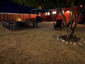 An outdoor patio area with a fire pit, seating, and a covered table.