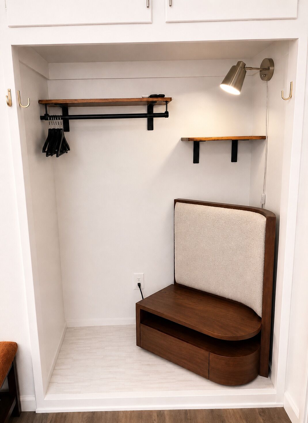 Une pièce de taille modeste, dotée d’une banquette intégrée, d’un porte-manteau suspendu et d’une étagère fixée au mur.