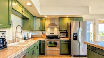 Une cuisine moderne avec des meubles de couleur verte, des appareils en acier inoxydable et un four encastré.